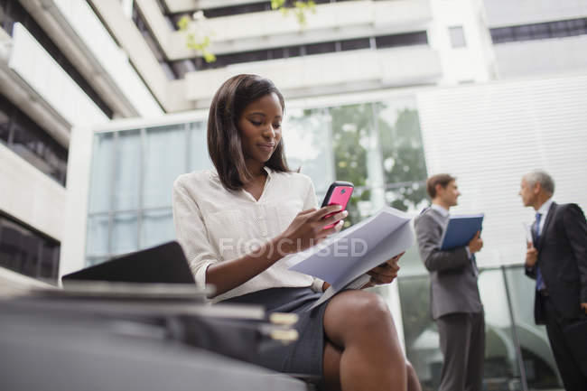 Donna d'affari seduta sul banco usando il cellulare all'esterno — Foto stock