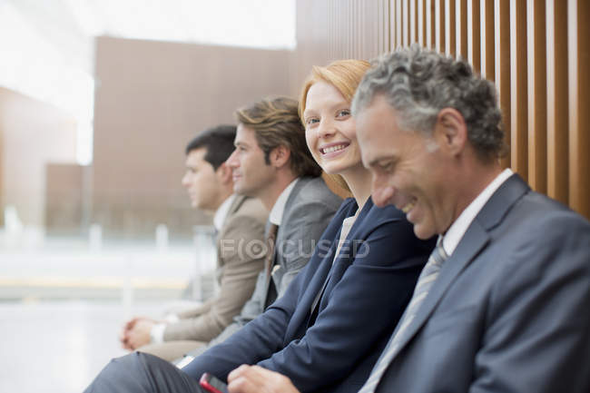 Portrait of smiling businesswoman sitting with businessmen — Stock Photo