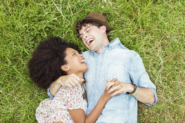 Riendo pareja yaciendo en la hierba - foto de stock