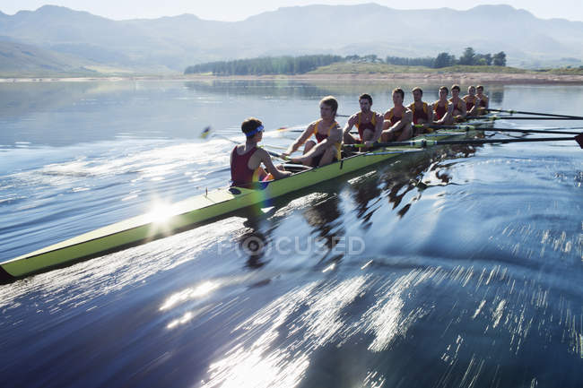 Rowing team rowing scull on lake — Stock Photo