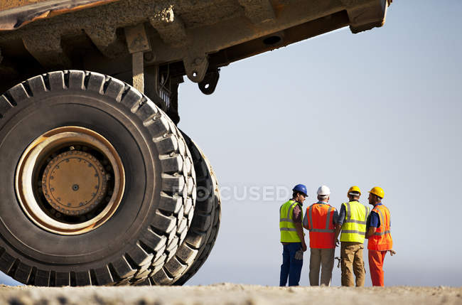 Workers talking by machinery on site — Stock Photo