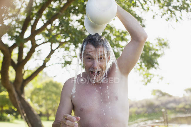 Retrato de homem entusiasta derramando água sobrecarga — Fotografia de Stock