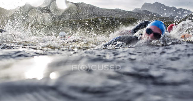 Уверенные и сильные триатлонисты, брызгающиеся в воде — стоковое фото