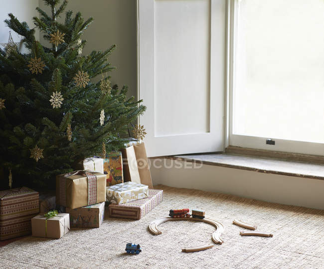 Train set and Christmas gifts under tree — Stock Photo