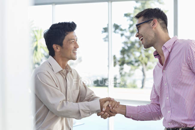 Businessmen shaking hands at modern office — Stock Photo