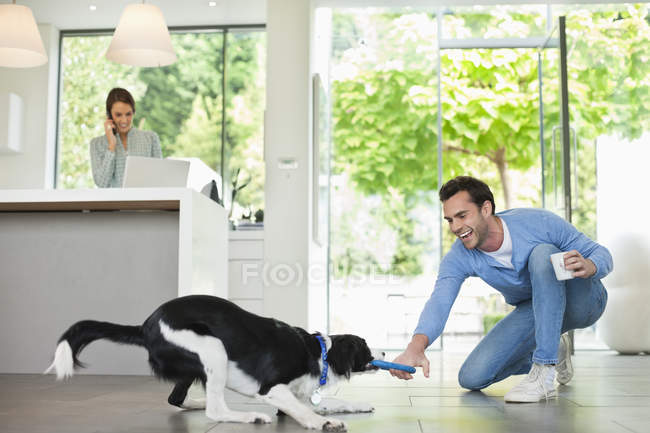 Homme jouant avec chien dans la cuisine à la maison moderne — Photo de stock