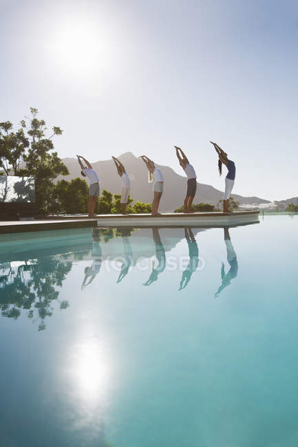 Giovani persone attraenti che praticano yoga a bordo piscina — Foto stock