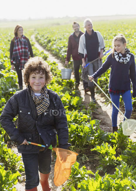 Portrait smiling boy with net walking in vegetable garden with family — Stock Photo