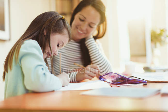 Мама смотрит дочь делать домашнее задание — стоковое фото