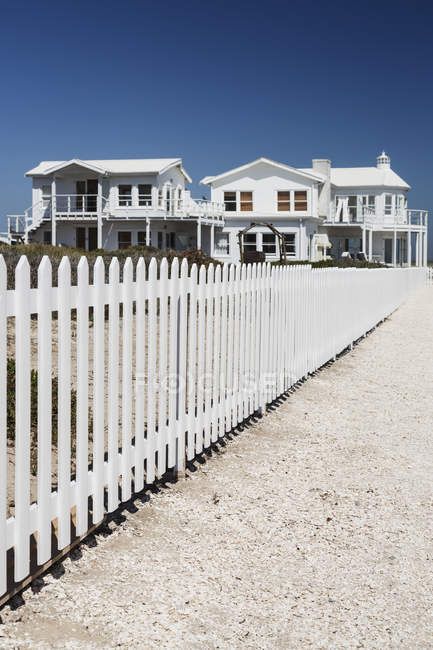Білий паркан з пікету, що веде до пляжних будинків — стокове фото