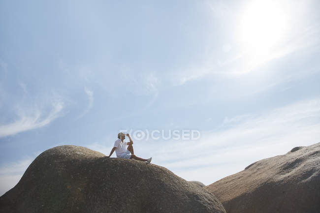 Человек, сидящий на скале — стоковое фото