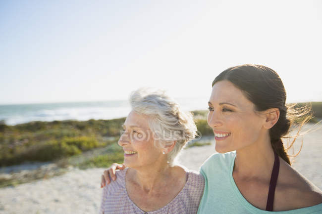 Mother and daughter smiling on sunny beach — Stock Photo