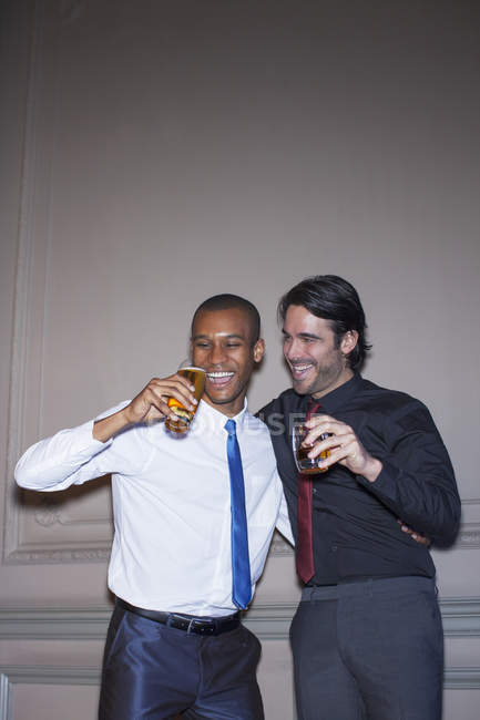 Gut gekleidete Männer umarmen sich und trinken Bier und Cocktail — Stockfoto