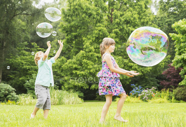 Enfants heureux jouant avec des bulles à l'extérieur — Photo de stock