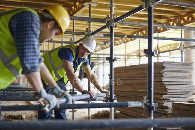 Trabajadores de la construcción ajustando barra metálica en obra - foto de stock