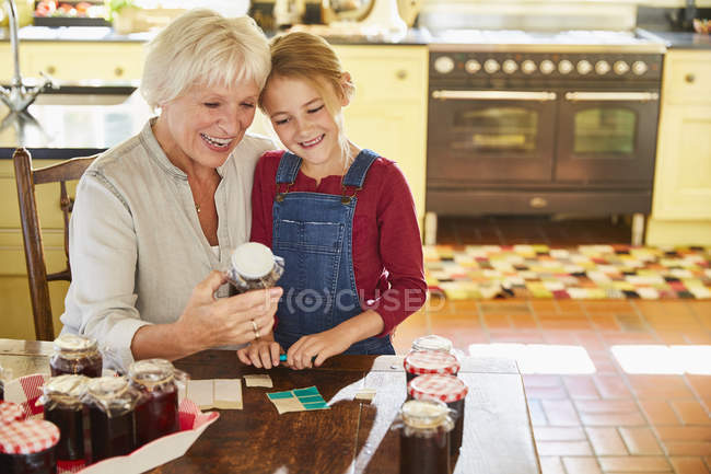 Grand-mère et petite-fille en conserve confiture dans la cuisine — Photo de stock