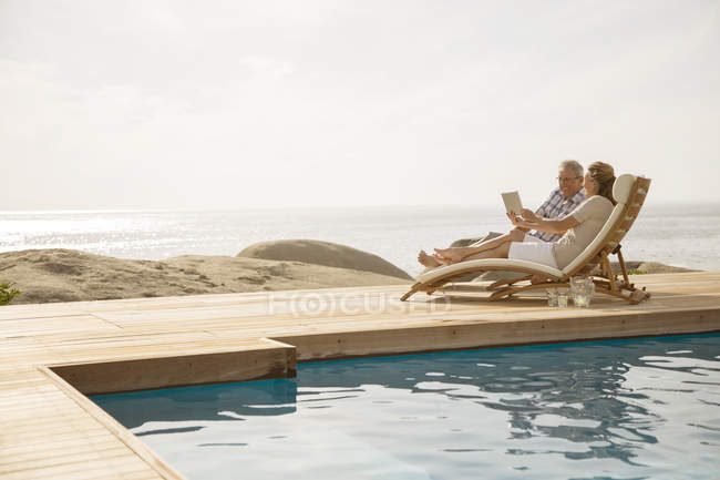 Couple plus âgé relaxant au bord de la piscine — Photo de stock