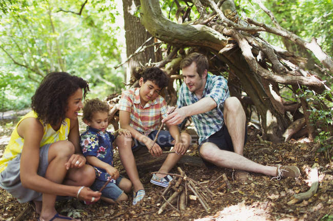 Familia haciendo pequeña fogata en el bosque con palos - foto de stock