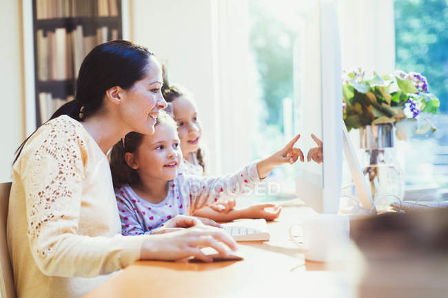 Mother and daughters using computer — Stock Photo