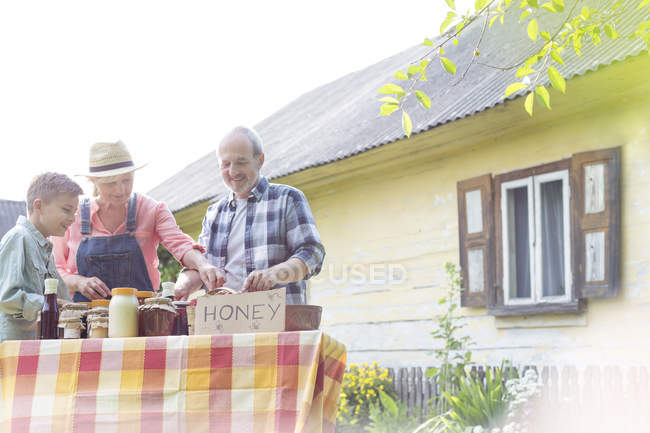 Abuelos y nieto vendiendo miel - foto de stock