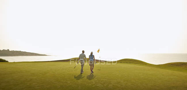 Кавказская пара играет в гольф на поле — стоковое фото