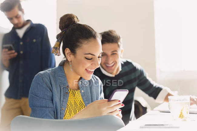 Lächelnde junge Geschäftsleute, die mit dem Handy SMS schreiben — Stockfoto