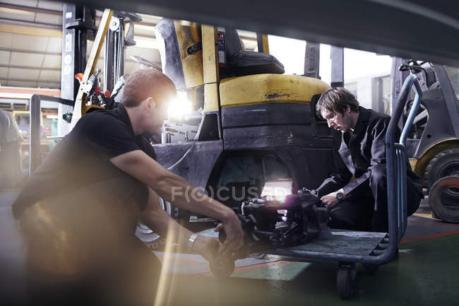 Mechanics fixing forklift in auto repair shop — Stock Photo