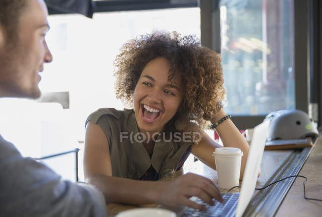Энтузиастка смеется над ноутбуком в кафе — стоковое фото