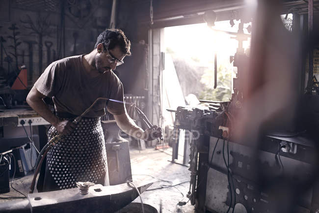 Blacksmith using blow torch in forge — Stock Photo