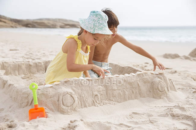 Bambini che fanno castello di sabbia sulla spiaggia — Foto stock