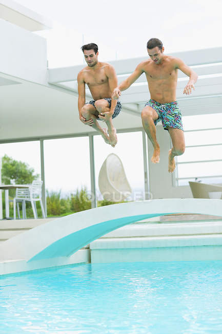 Homens jovens pulando na piscina — Fotografia de Stock
