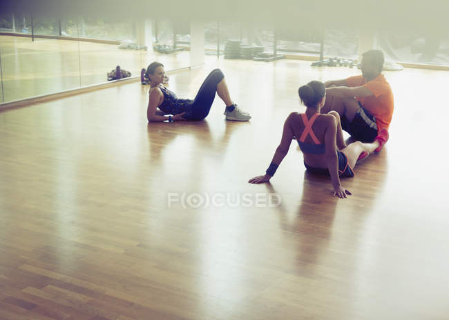 Friends resting and talking on gym studio floor — Stock Photo