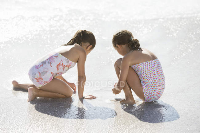 Girls playing together in surf on beach — Stock Photo