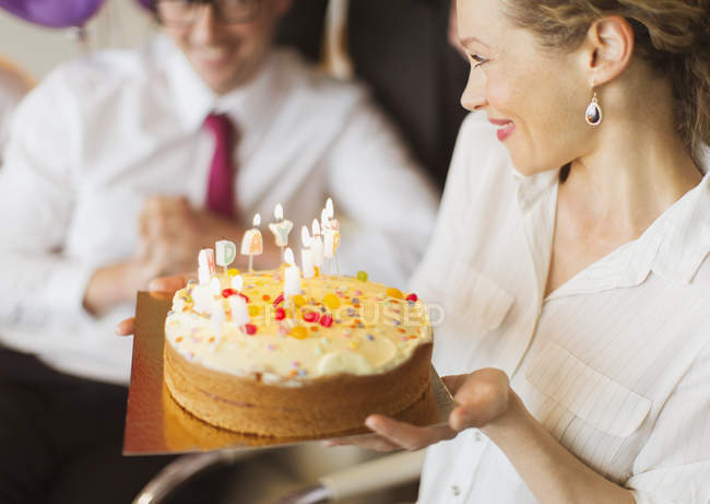 Smiling businesswoman holding birthday cake with candles — Stock Photo