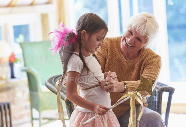 Grandmother fitting granddaughter with wings — Stock Photo
