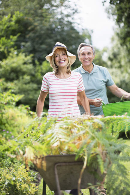 Couple aîné avec brouette et seau dans le jardin — Photo de stock