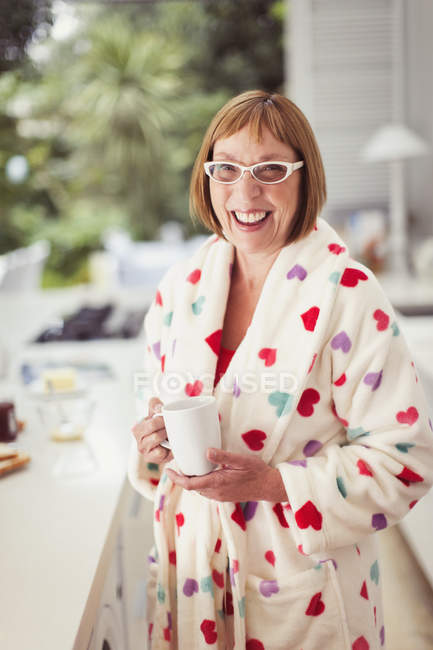 Portrait smiling mature woman drinking coffee in bathrobe — Stock Photo