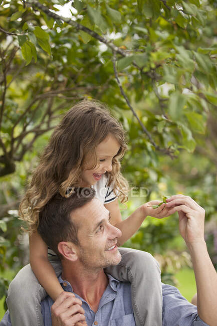 Father carrying daughter on shoulders outdoors — Stock Photo