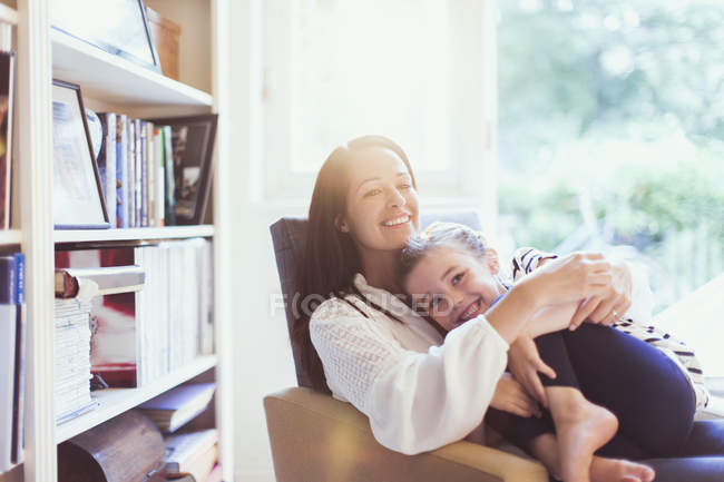 Affectionate mother hugging daughter in armchair — Stock Photo