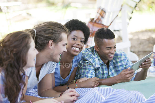 Friends using digital tablet on blanket — Stock Photo