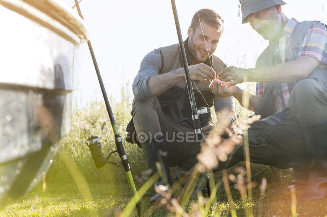 Padre e hijo adulto preparando líneas de pesca - foto de stock