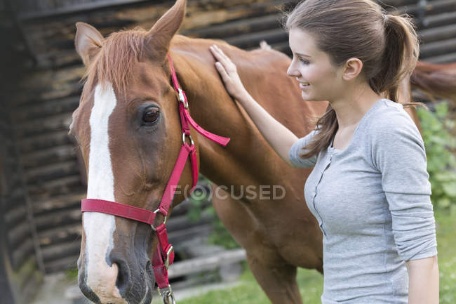 Mulher acariciando cavalo no pasto — Fotografia de Stock
