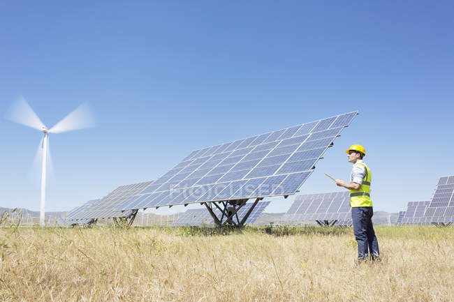 Trabalhador examinando painéis solares na paisagem rural — Fotografia de Stock