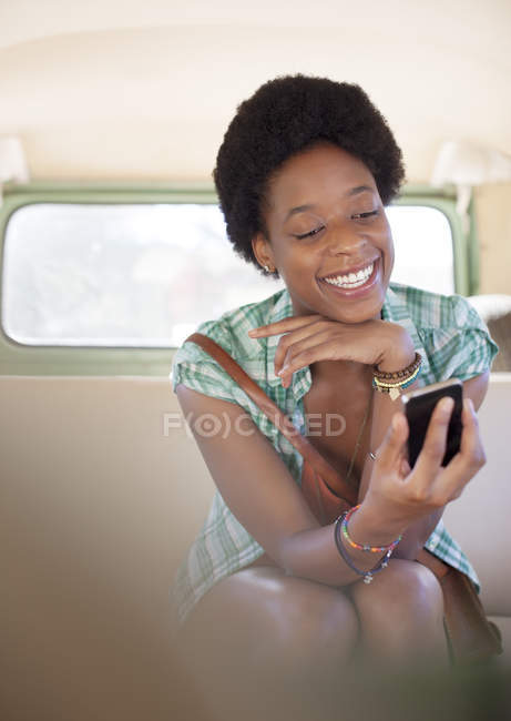 Woman using cell phone in back seat of camper van — Stock Photo