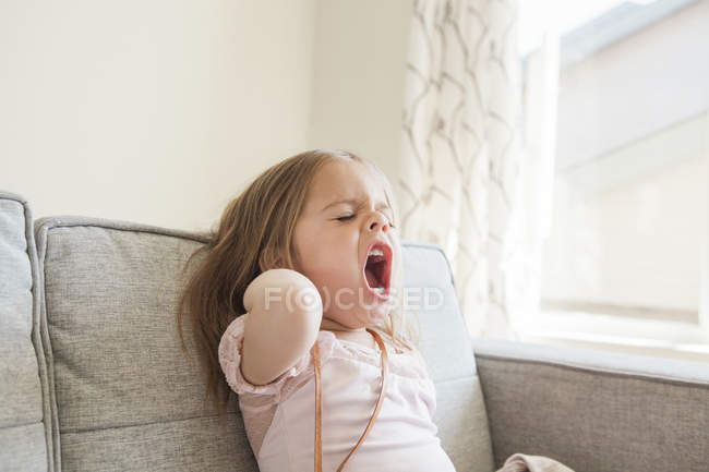 Toddler girl yawning on sofa — Stock Photo