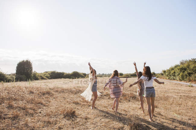 Безтурботні дівчата танцюють на сонячному сільському полі — стокове фото