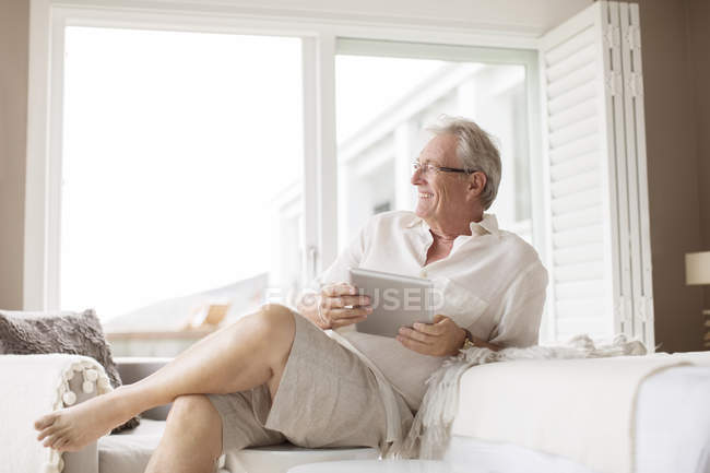 Взрослый мужчина с цифровым планшетом в спальне — стоковое фото