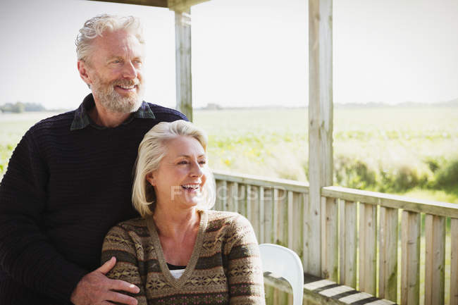Усміхнена старша пара дивиться далеко на сонячний ганок — стокове фото