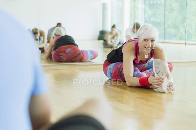 Fitness instructor leading class stretching leg — Stock Photo