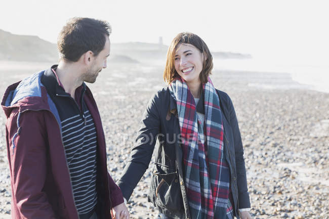 Couple souriant marchant sur la plage — Photo de stock
